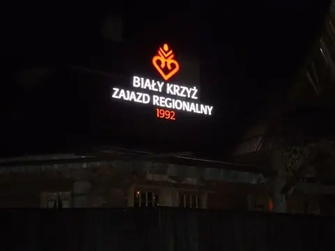 Podświetlany szyld Biały Krzyż nocą