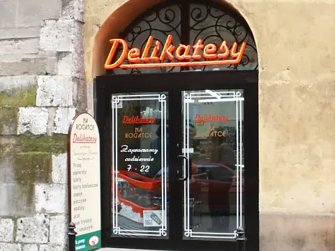 Neonowy szyld Delikatesy nad drzwiami