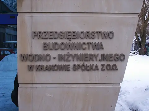 Tablica firmowa z literami na kamiennym słupie