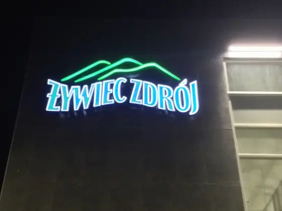 Świecące litery ŻYWIEC ZDRÓJ na budynku fabryki nocą